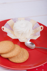 cream cheese in an environmentally friendly packaging made of wood with a round pastry on the red plate, top view, side view,