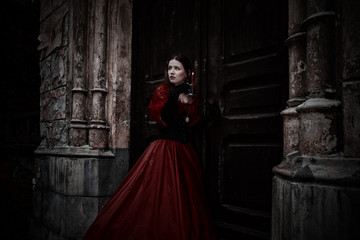 Mysterious woman in red Victorian dress with a candle