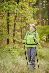 woman with hiking equipment walking in forest