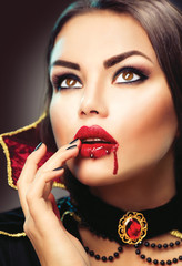 Halloween vampire woman portrait. Beauty sexy vampire lady with blood on her mouth