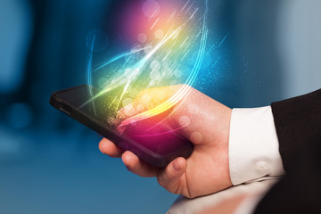 Hand holding smart phone with abstract glowing lines