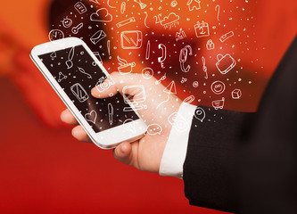 Hand holding smartphone with hand drawn media icons and symbols