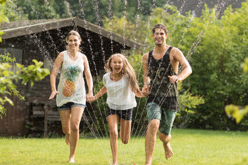 Familie läuft über einen Wassersprenger