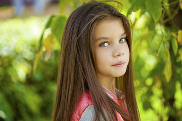 Beautiful little girl on green background of summer city park