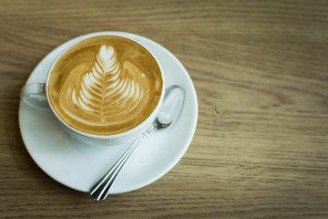 Hot latte art coffee cup on wooden table, vintage and retro styl