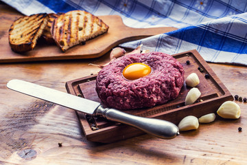 Raw beef .Tasty Steak tartare. Classic steak tartare on wooden board. Ingredients: Raw beef meat salt pepper egg garlic chilli herb decoration and toast bread