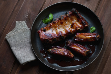 Frying pan with baked pork ribs, high angle view, studio shot