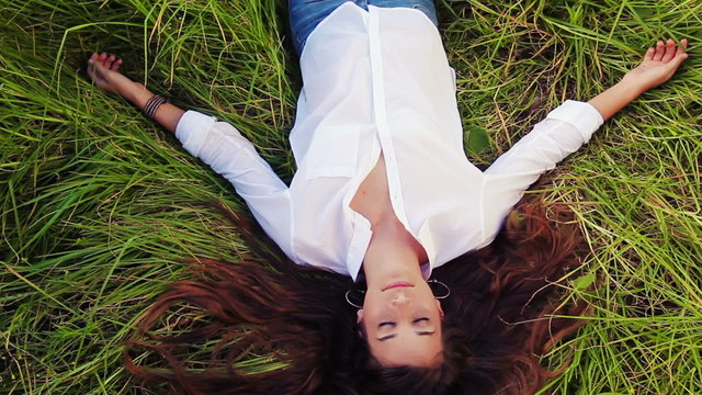 Beautiful Girl Lying on the Meadow and Dreaming. Enjoy Nature. Beautiful Brunette.