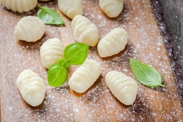 homemade raw gnocchi  with flour and fresh basil closeup