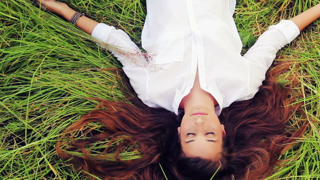 Beautiful Girl Lying on the Meadow and Dreaming. Enjoy Nature. Beautiful Brunette. Eyes Closed.