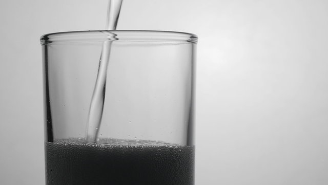 Soda water being poured into glass against white background. 4K UHD 2160p footage.

