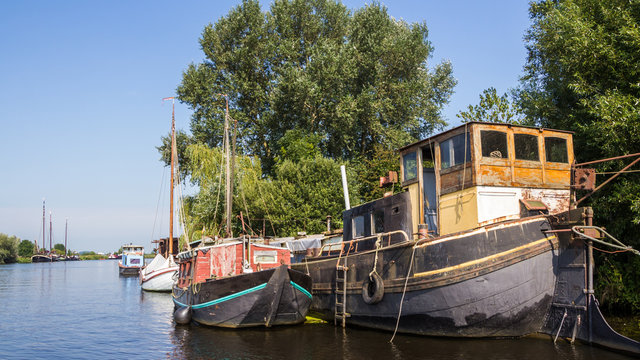 A big old barge, a sailboat and a cabin boat on the side next to