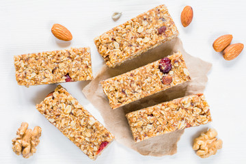 Fototapeta na wymiar Granola bar or energy bar with oats, dates and nuts on white wooden background, top view