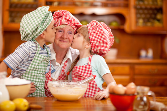 grandson and granddaughter kiss their grandmother in the kitchen