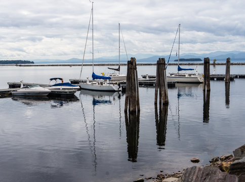 sail boats docked at pier with Adirondack mountains across the lake
