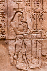 Fototapeta na wymiar Egyptian hieroglyphics on the stone wall. Ancient stone carved E