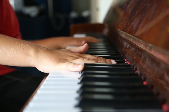 Hands of kid playing on a piano keyboard shot from above