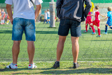 Naklejka premium Fathers watching their sons playing soccer game