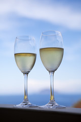 A restaurant table on a beach with glasses of fresh white wine.