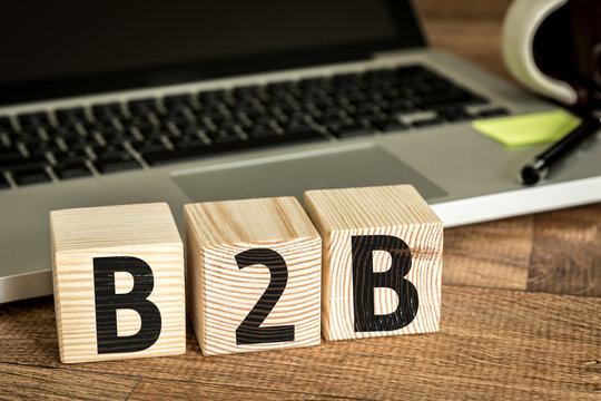 B2B written on a wooden cube in front of a laptop