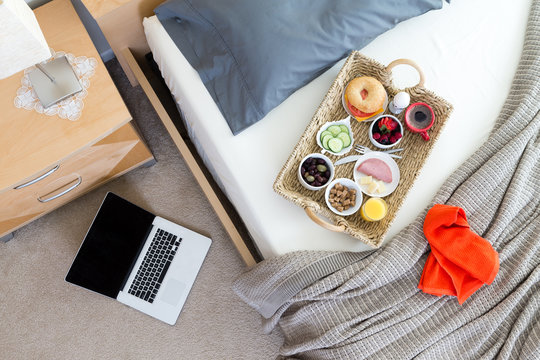 Laptop on Floor Beside Bed with Breakfast Tray