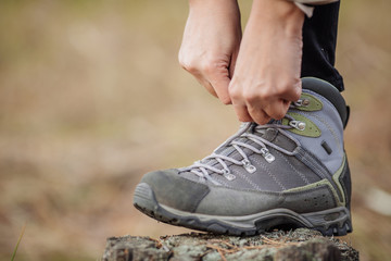  woman on a hiking trail ties the shoelace on her walking shoe,