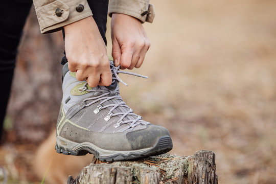  woman on a hiking trail ties the shoelace on her walking shoe,