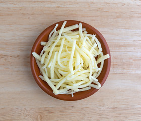 Portion of natural white mild cheddar cheese in bowl