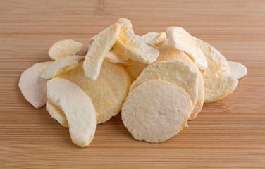 Dried peach slices on a wood cutting board.