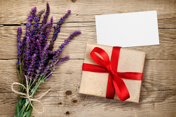 Flowers of salvia and gift box with visiting card on wooden background