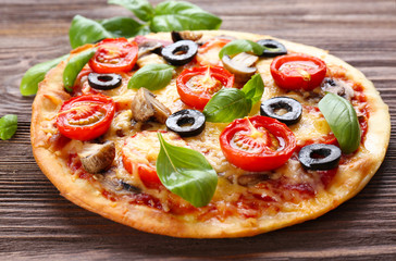 Tasty pizza with vegetables and basil on table close up