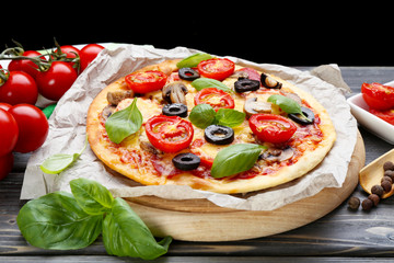 Tasty pizza with vegetables and basil on table close up