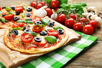 Tasty pizza with vegetables and basil on table close up