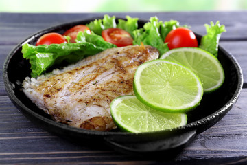 Dish of fish fillet with salad and lime on table close up