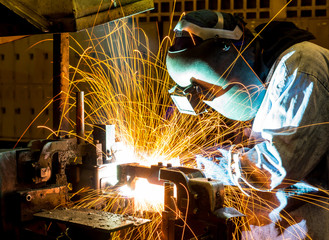 Fototapeta sparks while welder uses torch to welding obraz
