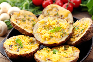 Baked potatoes with cheese and mushrooms on plate close up
