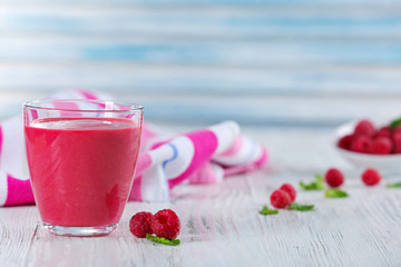 Glass of raspberry milk shake with berries on wooden table close up