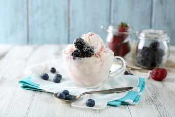 Delicious ice cream with fresh frozen berries, on color wooden background