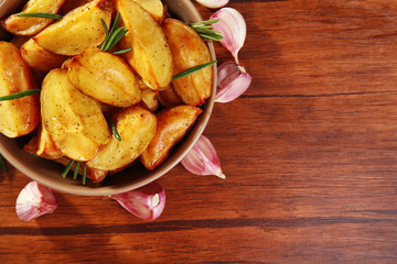 Baked potato wedges on wooden table, top view