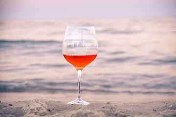 Romantic glass of wine sitting on the beach at colorful sunset