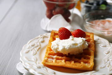 Sweet homemade waffles on plate, on color wooden background