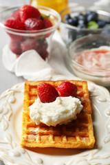 Sweet homemade waffles on plate, on color wooden background