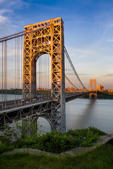 George Washington Bridge crossing the Hudson River connecting Fort Lee, New Jersey and Upper Manhattan, New York City. The towers of the suspension bridge are lit by the sunset light.