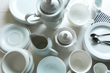 Set of white ceramics dishes on wooden table, closeup