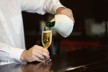 Bartender pouring champagne into glass, close-up