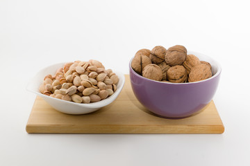 platefuls of different nuts stand on a plate on a white backgrou