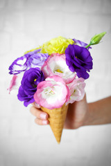 Woman's hand holding wild flowers in wafer on light wall background