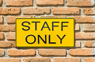 Staff only sign on brick wall.