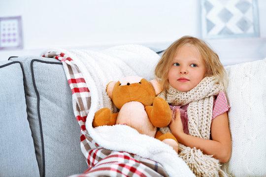 Little girl with sore throat holding toy bear closeup