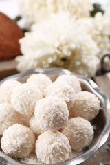 Homemade sweets in coconut flakes and fresh coconut on tray, close-up